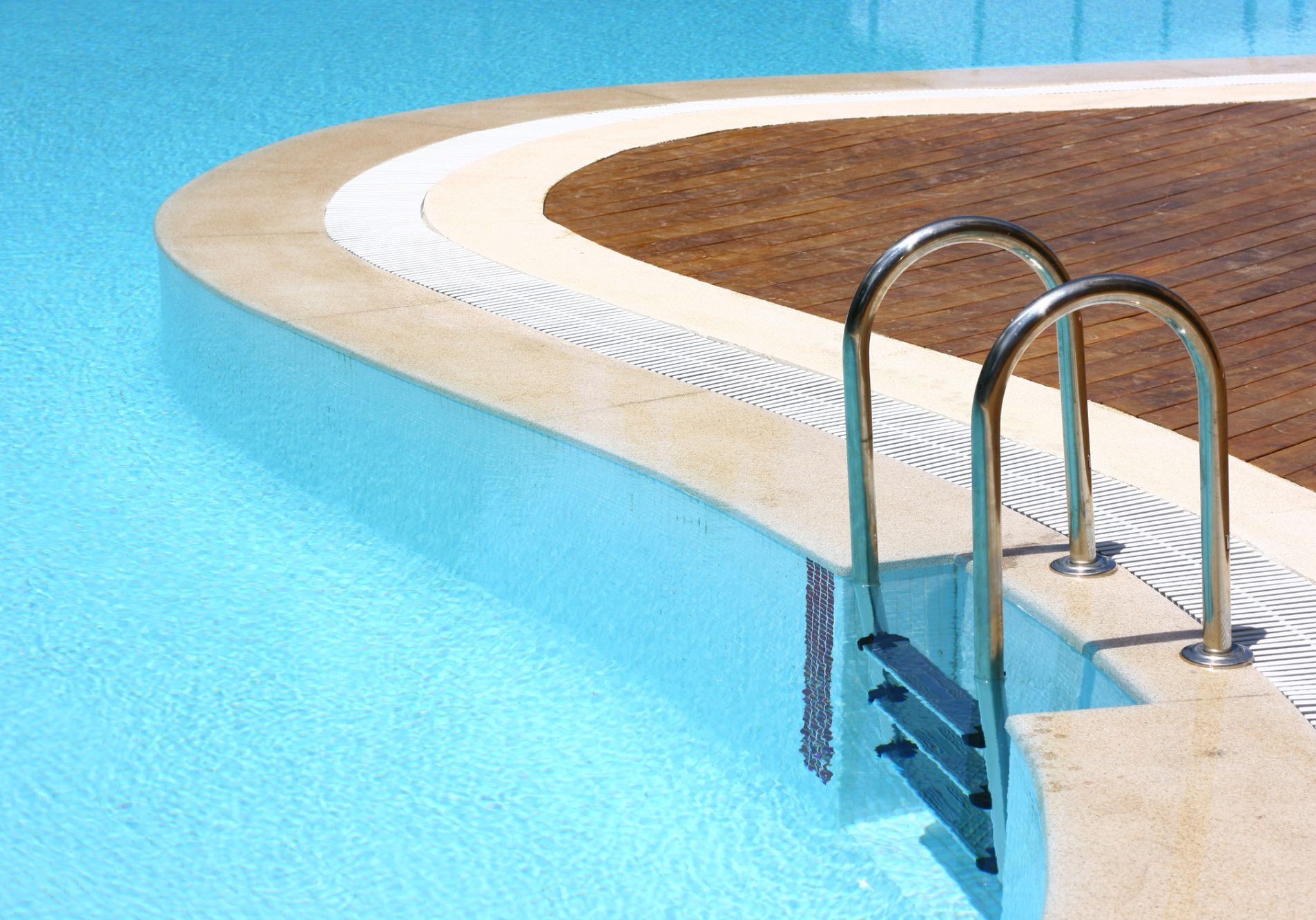 dreamstime_m_2865022 Summer resort swimming pool in a sunny day. The pool is S shaped, has a clear blue bottom and stainless steel stairs. The walking area is made of teak wood.