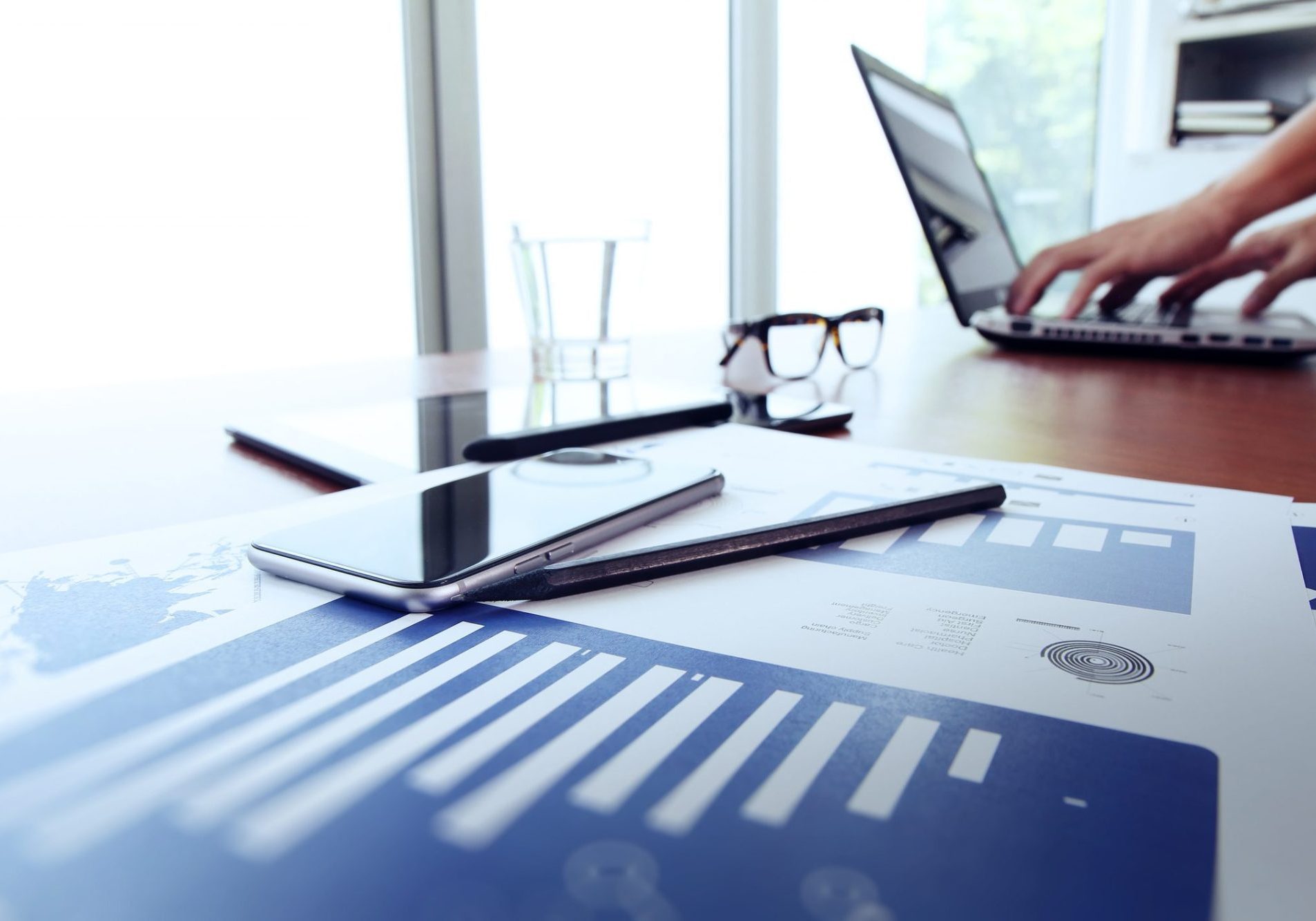 dreamstime_m_54208335 Business documents on office table with smart phone and digital tablet and man working in the background